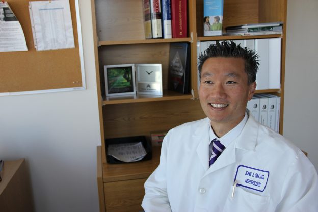 Dr. John Sim in front of bookcase.